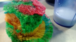 Pink, green, and yello partially eaten muffin