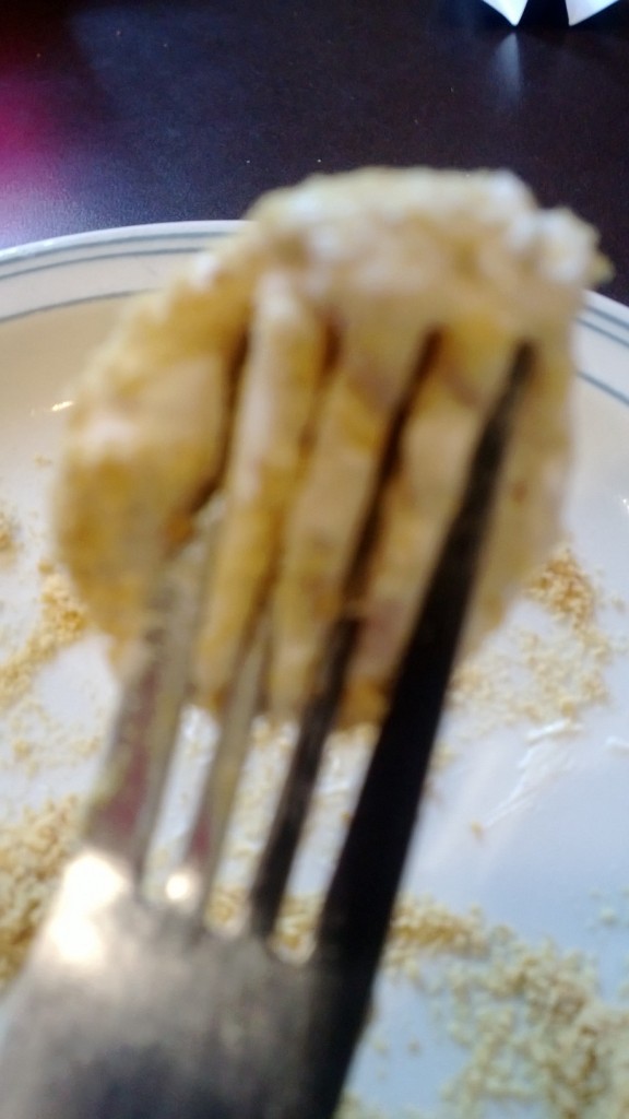 A goupy substance stuck to a fork hovering above a plate.